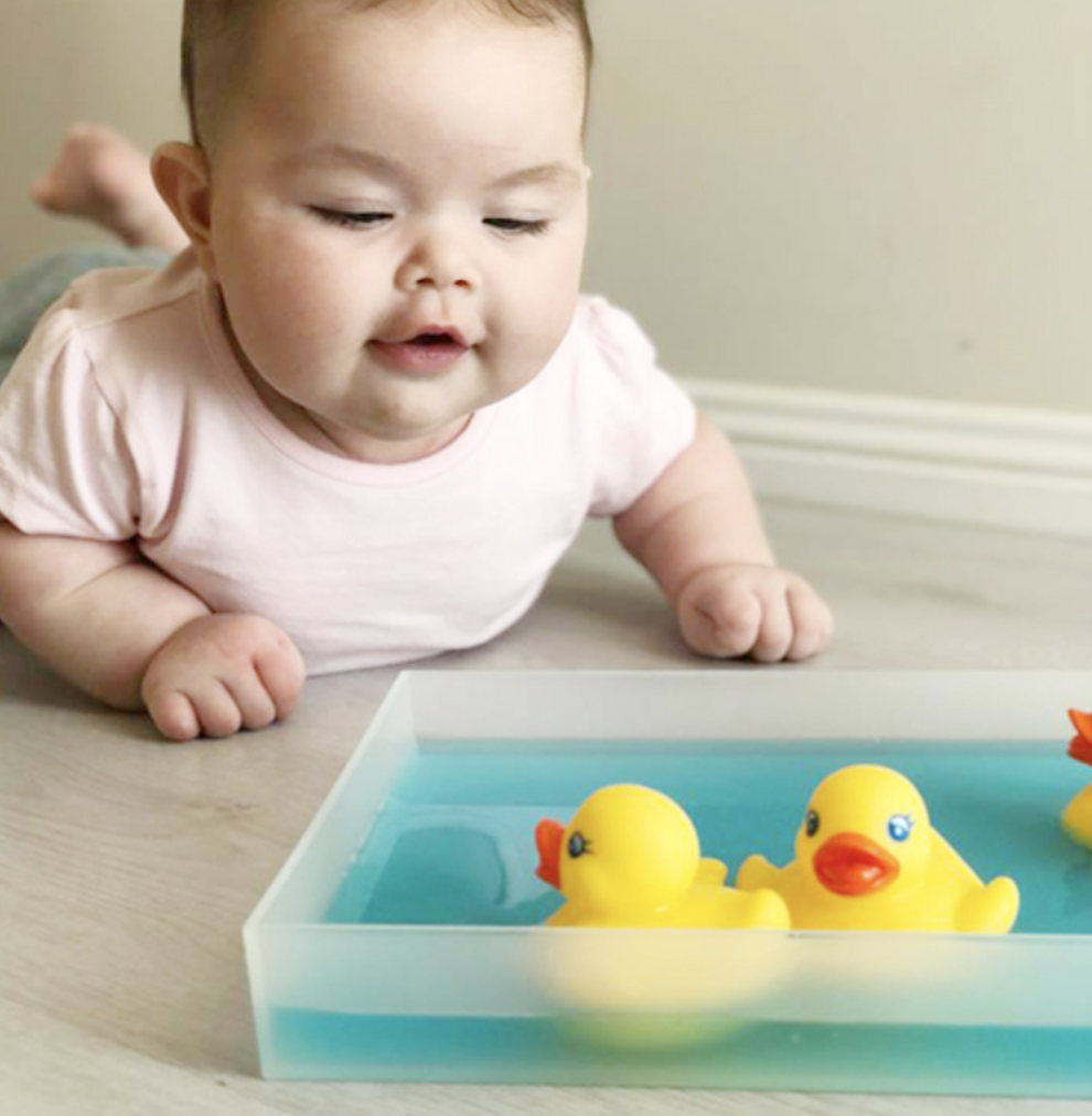 Baby on tummy play with water and rubber duckys